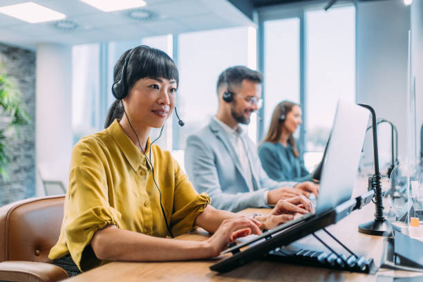 Shot of call center operators working in the office. Female call center agent working with her colleagues in modern office. Smiling beautiful businesswoman working in call center.